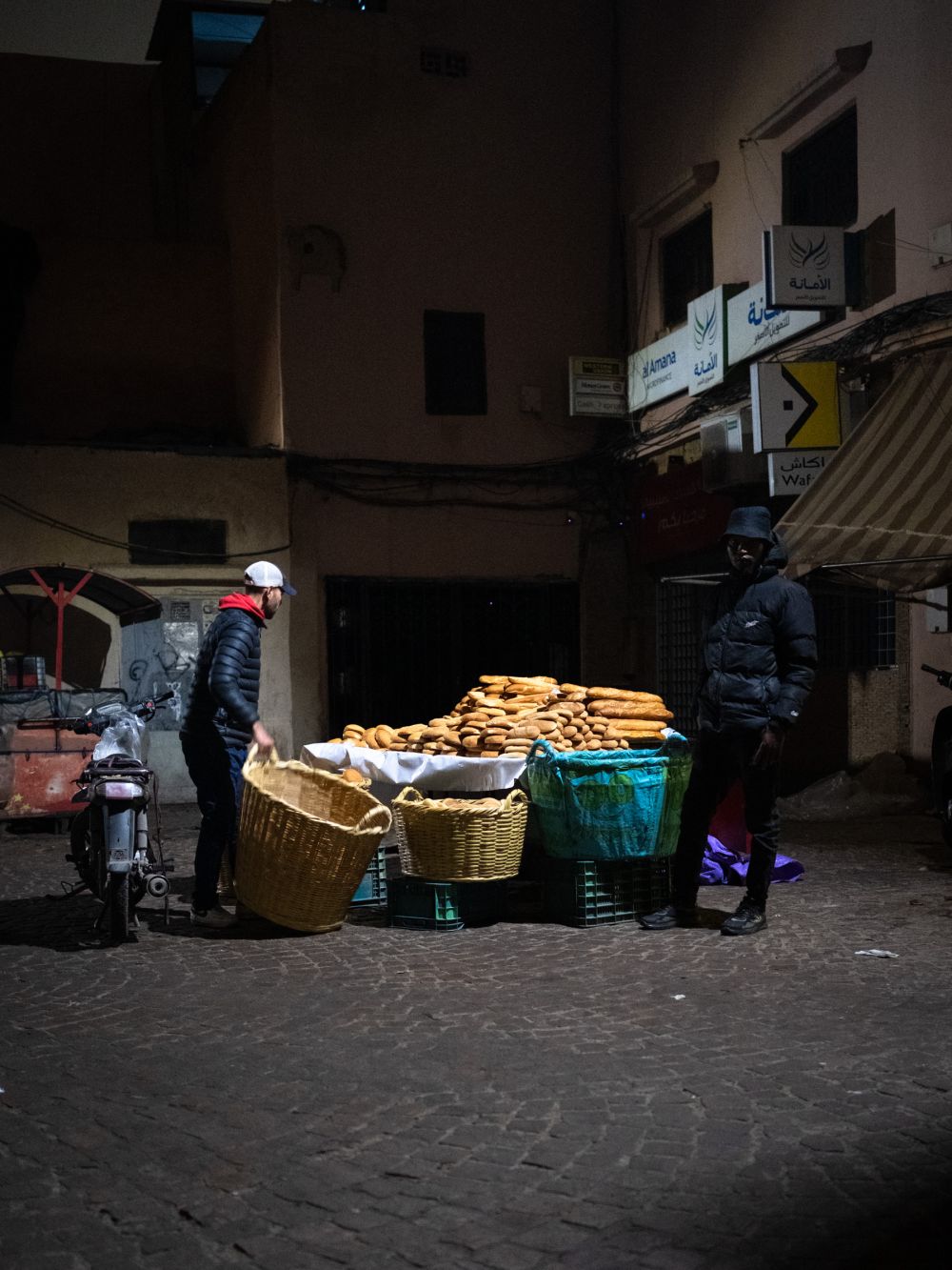 Two men tend to a street bread stall in the Medina, stacks of sesame loaves piled high on the table. One of the few signs of trade at this early hour.